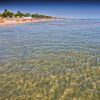 Spiaggia con acqua limpida e cielo blu.