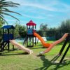 Parco giochi con scivoli e altalene su prato.