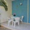 Tavolino esterno con sedie bianche e parete blu.