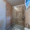 Bagno con doccia in vetro e pareti beige.