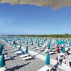 Spiaggia con file di lettini e ombrelloni verdi.