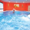 Piscina coperta con pareti arancioni e persona che nuota.