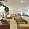 Area lounge con divani in rattan e cuscini chiari, piante sparse.