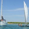 Due barche a vela in mare, spiaggia nello sfondo.