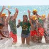 Gruppo di persone che giocano in mare, spruzzi d'acqua.