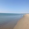 Spiaggia vuota con mare calmo e cielo sereno.