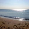 Spiaggia con mare calmo e persona in lontananza.