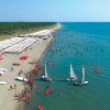 Spiaggia con barche e molte persone in mare.