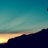 Persona su collina al tramonto con binocolo.