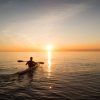 Una persona in kayak al tramonto sul mare calmo.