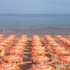 Ombrelloni arancioni su una spiaggia affollata.