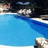 Piscina azzurra con lettini e ombrelloni blu.