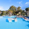 Piscina con sdraio e ombrelloni, circondata da alberi.