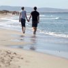 Coppia cammina mano nella mano sulla riva del mare.