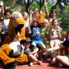 Gruppo di bambini con mascotte all'aperto, seduti su una panchina.