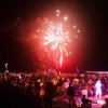 Fuochi d'artificio su spiaggia affollata di notte.