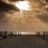 Alba con ombrelloni chiusi su spiaggia deserta.