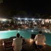 Musicisti suonano accanto a piscina illuminata di notte.